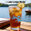 Glass with iced tea, lemon, and blue lake map on table near water.