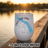 A white travel mug with a blue map of Eklutna Lake rests on a wooden dock.