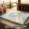 A rectangular glass cutting board with a Douglas Lake, Tennessee compass design rests on a wooden dock.