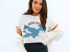 Woman wearing white t-shirt with blue Lake Arrowhead California map and compass graphic.