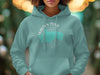 Teal hoodie with "Walden Pond, Massachusetts" circular graphic and compass rose outline.