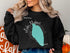 Black crewneck sweatshirt with "Beautiful Lake Mohave" and compass graphic.