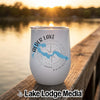 A white stainless steel wine tumbler with a compass and Alder Lake, Washington map graphic sitting on a wooden dock at sunset.