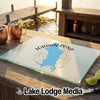 A glass cutting board featuring a blue map of Jordan Pond, Maine, resting on an outdoor wooden table.