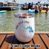 A white wine tumbler with a Pactola Lake South Dakota compass design sits on a wooden dock with a lake scene in the background.