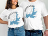 White t-shirts featuring "Hayden Lake Idaho" text, blue lake outline, and compass graphic.