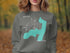 Grey sweatshirt with teal map outline of New York and compass graphic.