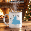 White mug with Lake St. Clair Michigan design, steaming coffee, fireplace, and Christmas tree.