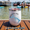 A white insulated tumbler with Skiatook Lake Oklahoma text stands on a wooden deck near a lake.