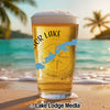 Glass of beer with "North Star Lake Minnesota" design on a beach at sunset.