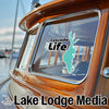 Cascade Life logo and Lake Lodge Media text on a boat window with wood trim.