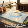 A glass cutting board rests on an outdoor wooden bar with a Lake Springfield compass map design.