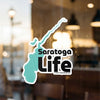 Saratoga Life sticker with teal outline on a window, © Lake Lodge Media LLC.