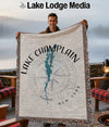 Man holding a woven blanket with Lake Champlain map and compass design.
