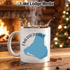 White mug with "Emerald Lake Canada" design next to a fireplace and Christmas tree.
