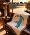 Blanket with Flathead Lake Montana map and compass design on a leather couch.