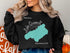 Black sweatshirt with teal outline of Lake Quinault and "Beautiful Lake Quinault Washington" text.