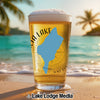 Beer glass with blue lake graphic and compass on a beach background.