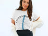 Woman wearing a white t-shirt with "Conesus Lake New York" and compass graphic.