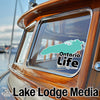 Aquamarine Ontario Life sticker on a wooden boat window, with Lake Lodge Media text and logo.
