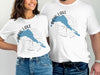 Two people wear white t-shirts with a blue Bow Lake graphic and compass design.
