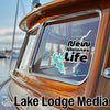 Sticker with "New Melones Life" text and a lake outline on a wooden boat window.