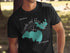 Black t-shirt with compass and teal outline of Brooks and Hess Lake, Michigan.