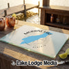 A rectangular glass cutting board with a Moraine Lake Alberta map design rests on a wooden outdoor bar.