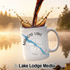 White mug with Măligne Lake and compass design, coffee pouring.