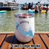 A white insulated tumbler with Lake Marion graphics rests on a wooden boat deck against a lake backdrop.
