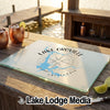 A glass cutting board featuring a blue Lake Oroville map and compass design sits on a wooden dock.