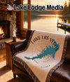 Woven blanket with Lake Las Vegas outline and compass on a leather sofa.