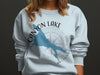 Light blue sweatshirt with a blue outline of Canyon Lake, Arizona, and compass graphic.