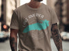 Taupe t-shirt with turquoise lake shape and compass graphic.