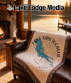 Blanket with Lake Kabetogama, Minnesota map and compass design on a leather couch.
