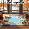 Glass cutting board featuring a map of Lake Pontchartrain, Louisiana, arranged with crackers, cheese, and pecans on a wooden table.