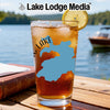 Glass of iced tea with lake shape and lemon slice on wooden table by water