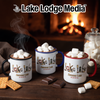Three mugs of hot chocolate with marshmallows sit before a fireplace with a jar of marshmallows.