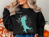 Black sweatshirt with turquoise Lake Quivira, Kansas map and compass graphic.