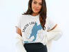 White t-shirt with "Snow Lake" graphics featuring a blue lake outline and compass.