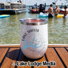 A white Lake Shasta California insulated wine tumbler sits on a wooden boat deck with people swimming in the background.