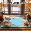 A glass cutting board featuring a map of Red Lake, Minnesota, surrounded by crackers, cheese, and nuts on a wooden table.