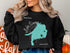 Black sweatshirt with turquoise Lake Simcoe map outline and "Beautiful Lake Simcoe Ontario" text.