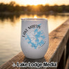 White insulated tumbler featuring a blue map of Lake Martin, Alabama, resting on a wooden dock at sunset.