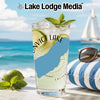 Glass of lemonade with lime and mint on a beach with a sailboat and sunglasses.