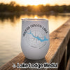 A white insulated wine tumbler with a compass and lake map graphic sits on a wooden dock.