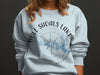 Light blue sweatshirt with Bull Shoals Lake, Arkansas graphic and compass rose.