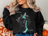 Black sweatshirt with "Beautiful Leelanau Lake Michigan" text and map illustration.