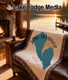 Woven blanket with Lake Almanor California map on a leather couch.