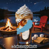 Glass with whipped cream, caramel, and ice, by a campfire at night.